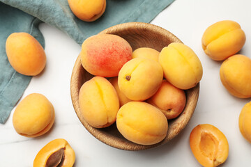 Fresh ripe apricots in bowl on white marble table, flat lay