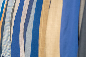 Close up of assorted fabric rolls in blue and beige tones, textile materials displayed in clothing market