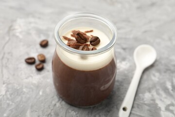 Delicious panna cotta with chocolate chunks and coffee beans on grey textured table, closeup