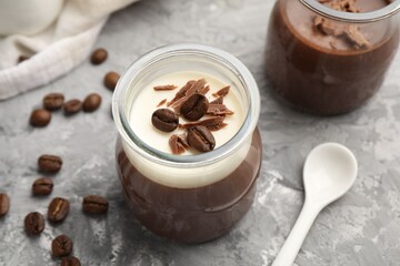 Delicious panna cotta with chocolate chunks and coffee beans on grey textured table, closeup