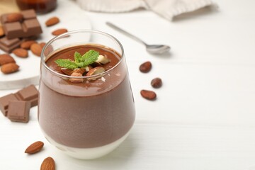 Delicious chocolate panna cotta with almonds and mint on white wooden table, closeup. Space for text