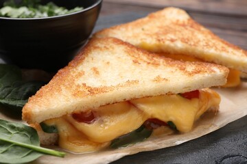 Delicious sandwiches with melted cheese and spinach on table, closeup