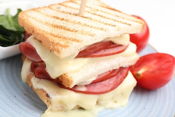 Delicious sandwich with melted cheese, ham, tomatoes and spinach on table, closeup