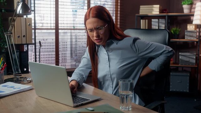 Caucasian business woman in office typing laptop feeling back spine ache pain tired overworked ill sick uncomfortable position backache sitting businesswoman female girl working suffer health problem