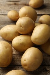 Many fresh potatoes on wooden table, closeup