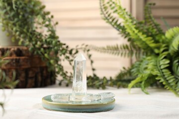 Aura. Beautiful crystals on beige fabric and green plants indoors