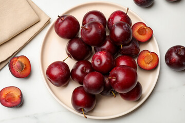 Ripe cherry plums on white marble table, flat lay