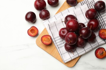 Ripe cherry plums on white marble table, flat lay