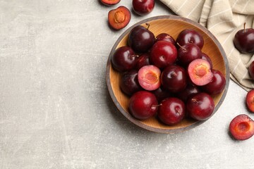Ripe cherry plums and bowl on grey textured table, flat lay. Space for text