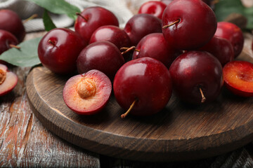 Whole and cut cherry plums on color wooden table, closeup