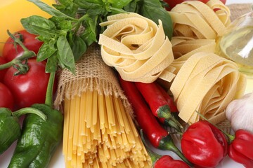 Different types of pasta and ingredients on table, closeup
