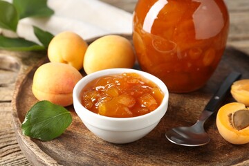 Tasty apricot jam and fresh fruits on wooden table, closeup