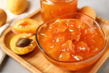 Tasty apricot jam and fresh fruits on light grey table, closeup