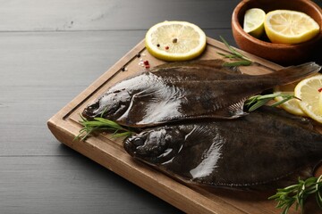Fresh raw flounder fish and spices on black wooden table, closeup. Seafood