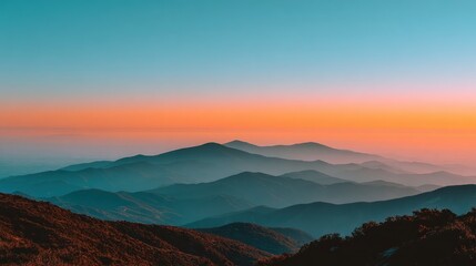 Fototapeta premium Mountain ridges fade to blue under a pink & orange sky. Airy, peaceful scene