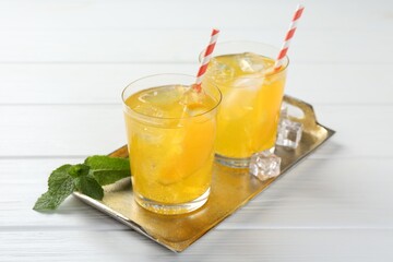 Refreshing soda water with orange slices in glasses and mint on white wooden table, closeup