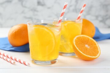 Refreshing soda water with orange slices in glasses and fresh fruits on white wooden table, closeup