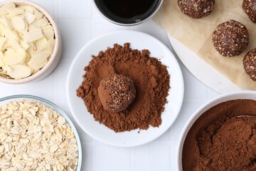 Making homemade candies. Chocolate balls and ingredients on white tiled table, flat lay