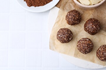 Making homemade candies. Chocolate balls and ingredients on white tiled table, flat lay. Space for text