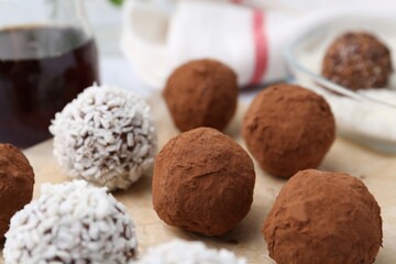Delicious homemade candies with cocoa powder and coconut flakes on table, closeup