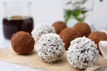 Delicious homemade candies with cocoa powder and coconut flakes on table, closeup