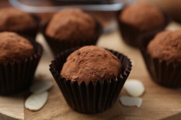Delicious homemade candies powdered with cocoa on wooden table, closeup