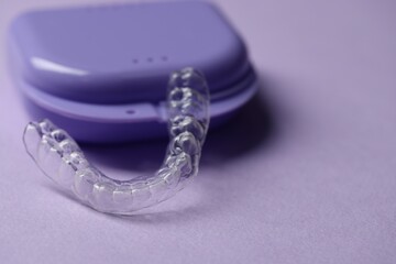 One clear aligner and retainer case on violet background, closeup