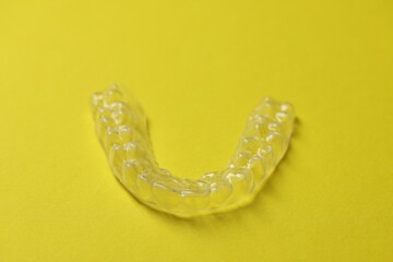 One clear aligner on yellow background, closeup