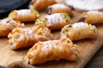 Delicious cannoli with cheese, nuts and powdered sugar on table, closeup
