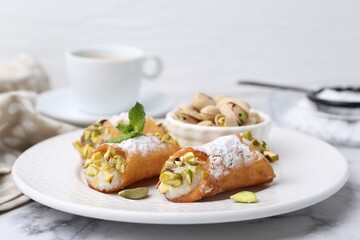Delicious cannoli with cheese, pistachios, powdered sugar and mint on white marble table, closeup