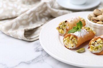 Delicious cannoli with cheese, pistachios, powdered sugar and mint on white marble table, closeup. Space for text