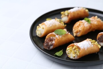 Delicious cannoli with cheese, nuts, powdered sugar, chocolate and mint on white table, closeup. Space for text