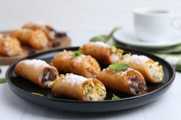 Delicious cannoli with cheese, nuts, powdered sugar, chocolate and mint on white table, closeup