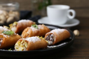 Delicious cannoli with cheese, nuts, powdered sugar, chocolate and mint on wooden table, closeup