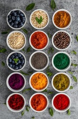 Assortment of colorful powders, seeds, nuts, and blueberries in bowls