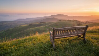 Wooden bench on a grassy hill overlooking distant mountains at sunset with a pastel colored sky above