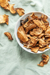 Dried mushrooms in a bowl resting on a green cloth