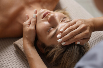 Beautiful woman receiving facial massage on couch, closeup
