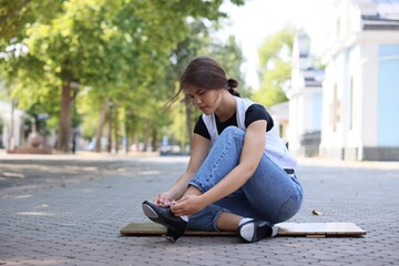 Teenage girl putting on tap shoes outdoors
