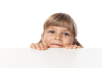 Curious little girl peeking over table against white background