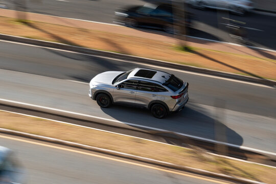 Panning shot of a silver Haval H6 GT driving on a highway, Aerial view of a modern chinese SUV in motion

