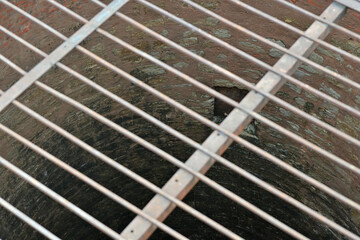 A grated metal cover spans over a deep, cylindrical brick well.