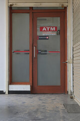 A glass door entry labeled "ATM" with a wooden frame and frosted panels.
