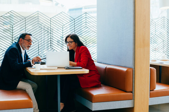Two senior professionals discussing work in a casual cafe setting