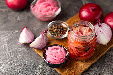 Pickled onions in a glass jar on the table. pickled red onion. Vegetarian spicy dish. Delicious homemade marinated pickled purple onions . Space for text. Copy space.