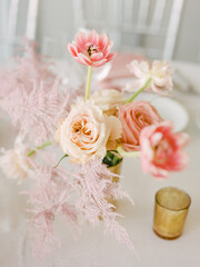 Beautiful floral arrangement featuring roses, tulips, and delicate greenery on an elegant dining table setting