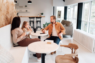 Father explains animatedly while daughter raises hand playfully, showcasing dynamic family...