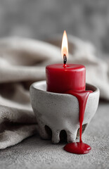 Close-up of a cherry red candle dripping wax in a textured holder against a soft background