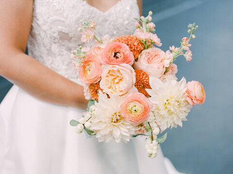 Bride holding a beautiful bouquet of pink and white flowers during a wedding ceremony in a charming setting