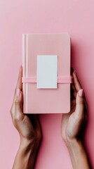 Obraz premium Hands holding a pink notebook with a white card on pink background - Concept of therapeutic Laziness 